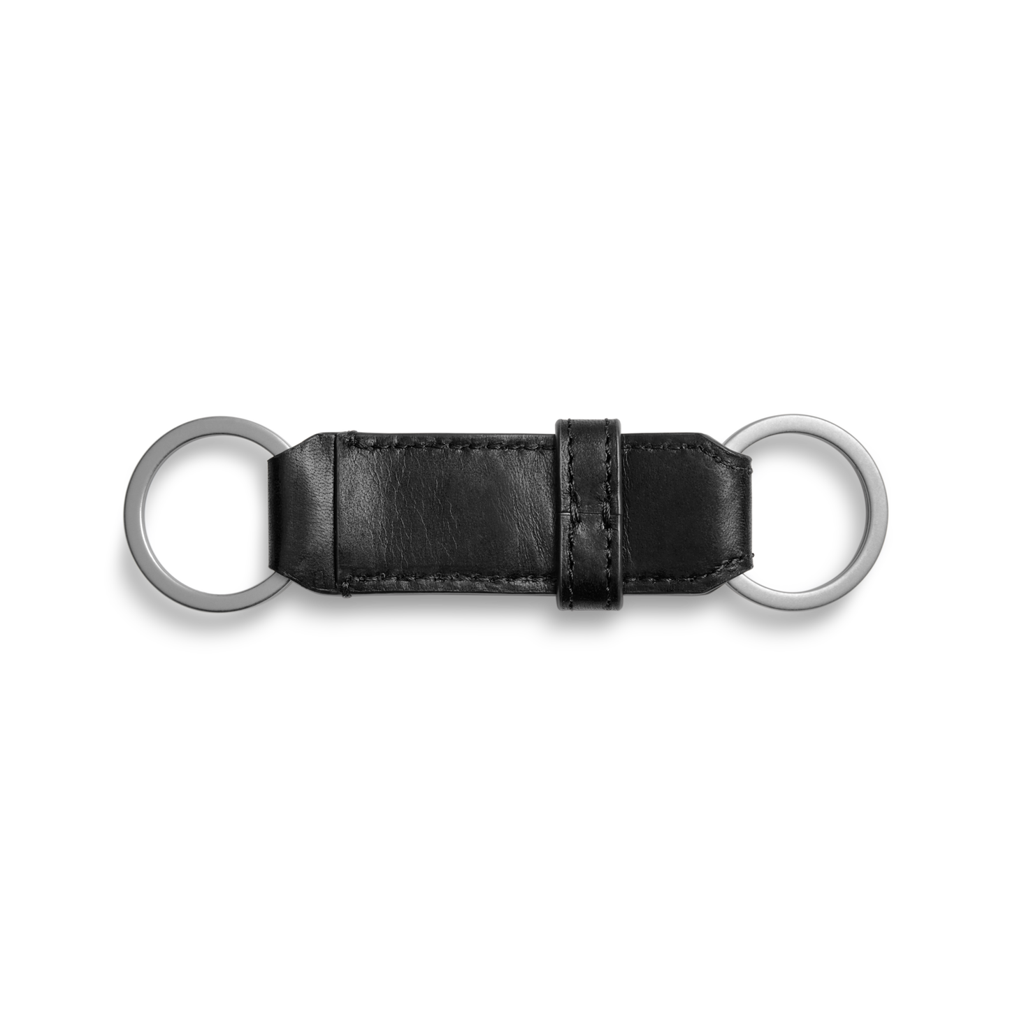 The Shinola Leather Valet Key Fob in black features a rectangular leather section with visible stitching, two silver metal rings at each end, and a matching leather loop near one end. Shown against a plain white background.
