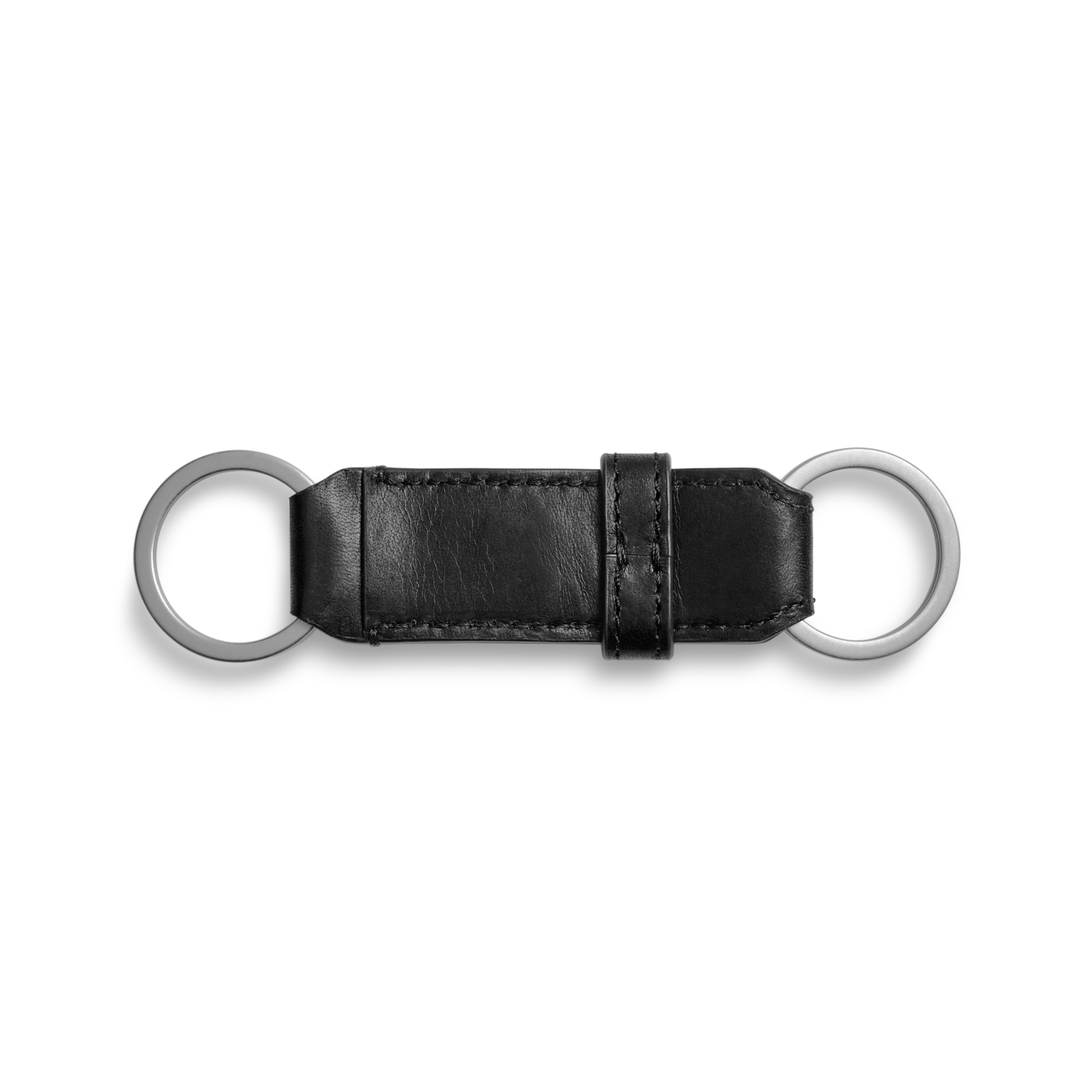 The Shinola Leather Valet Key Fob in black features a rectangular leather section with visible stitching, two silver metal rings at each end, and a matching leather loop near one end. Shown against a plain white background.