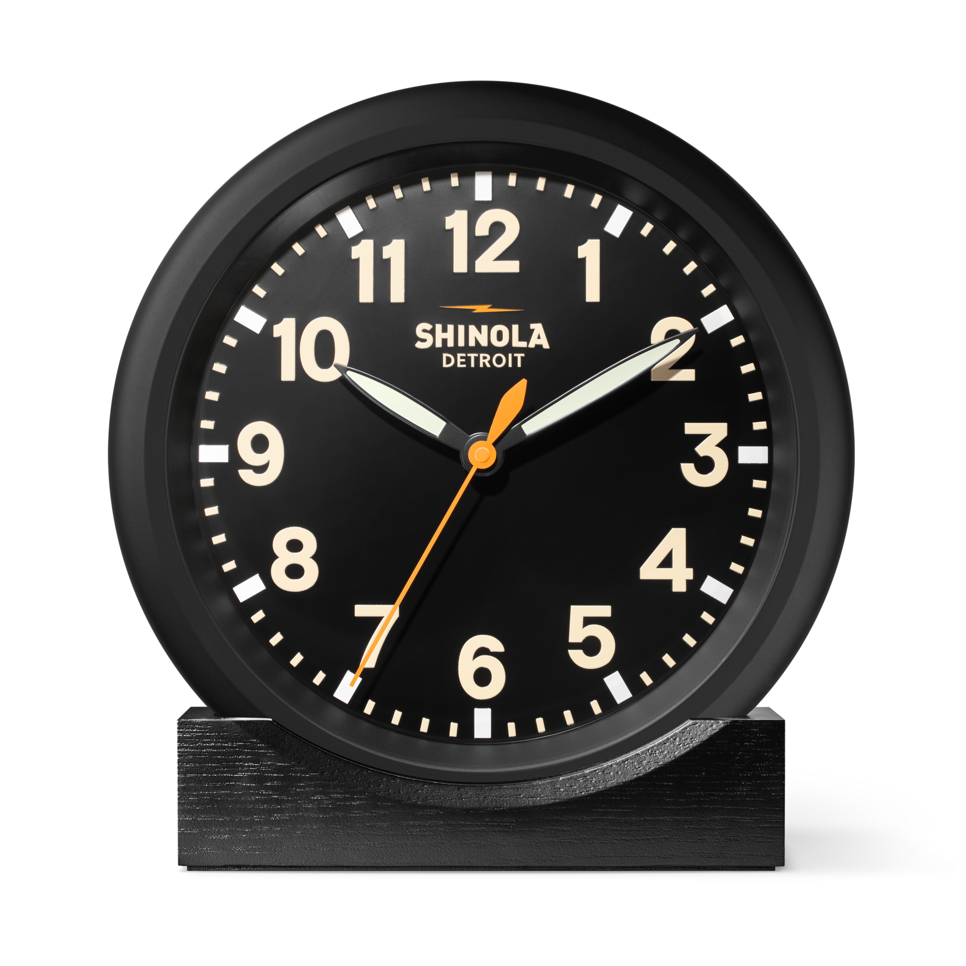 The Shinola 14" Runwell Clock - Black features a matte black dial with white numbers, hands, an orange second hand, "Shinola Detroit" on the face, and sits on a matching rectangular base. The time shown is 10:10:35. Inspired by the Runwell Wall Clock.