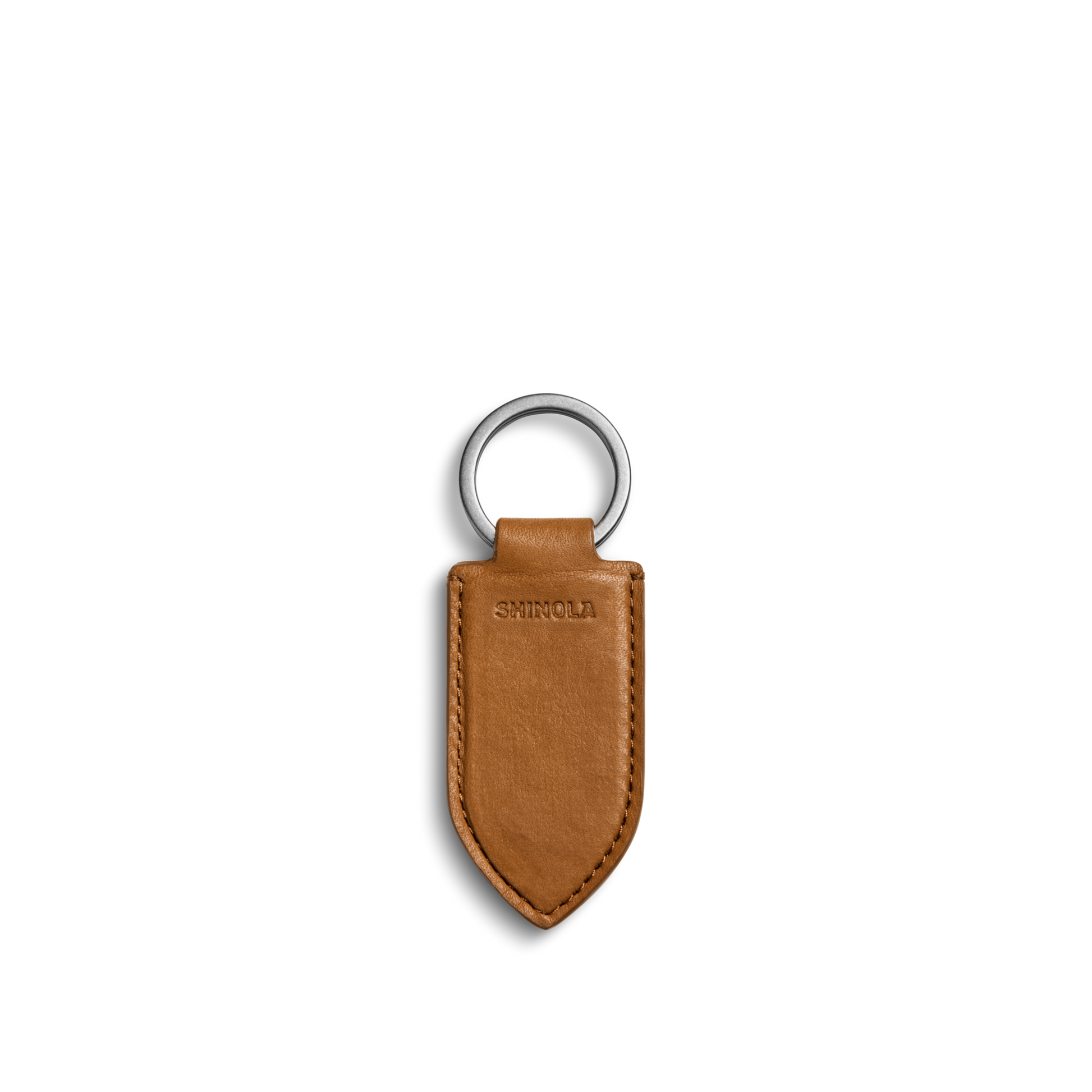 The Leather Monogram Key Fob - Tan by Shinola is a brown leather keychain with a pointed tip, silver metal ring, and the word SHINOLA embossed in the center, shown on a plain white background.