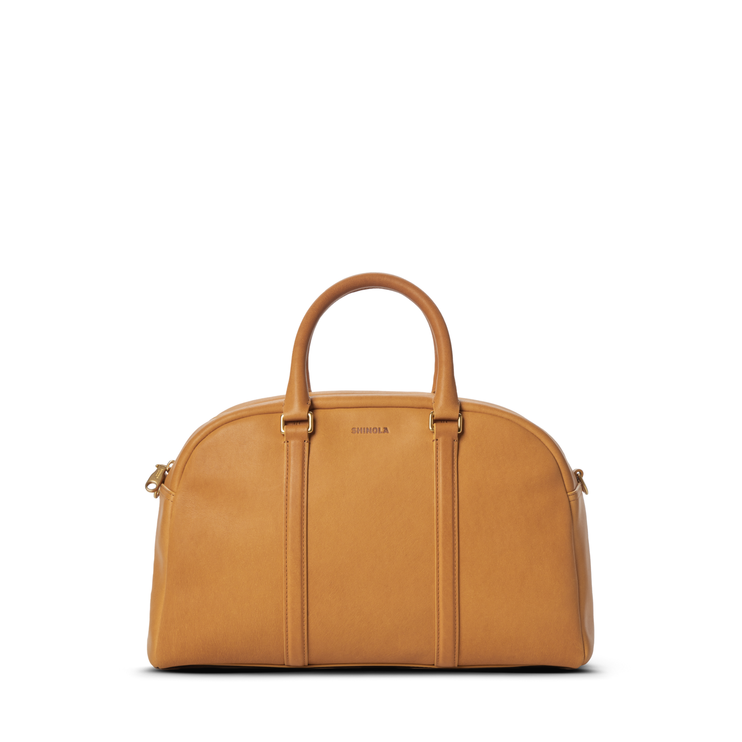 The Shinola Runwell Satchel - Honey is a tan premium natural leather duffel bag with two rounded handles, gold hardware, and a zipper closure. The front features the embossed brand name, photographed on a plain white background.