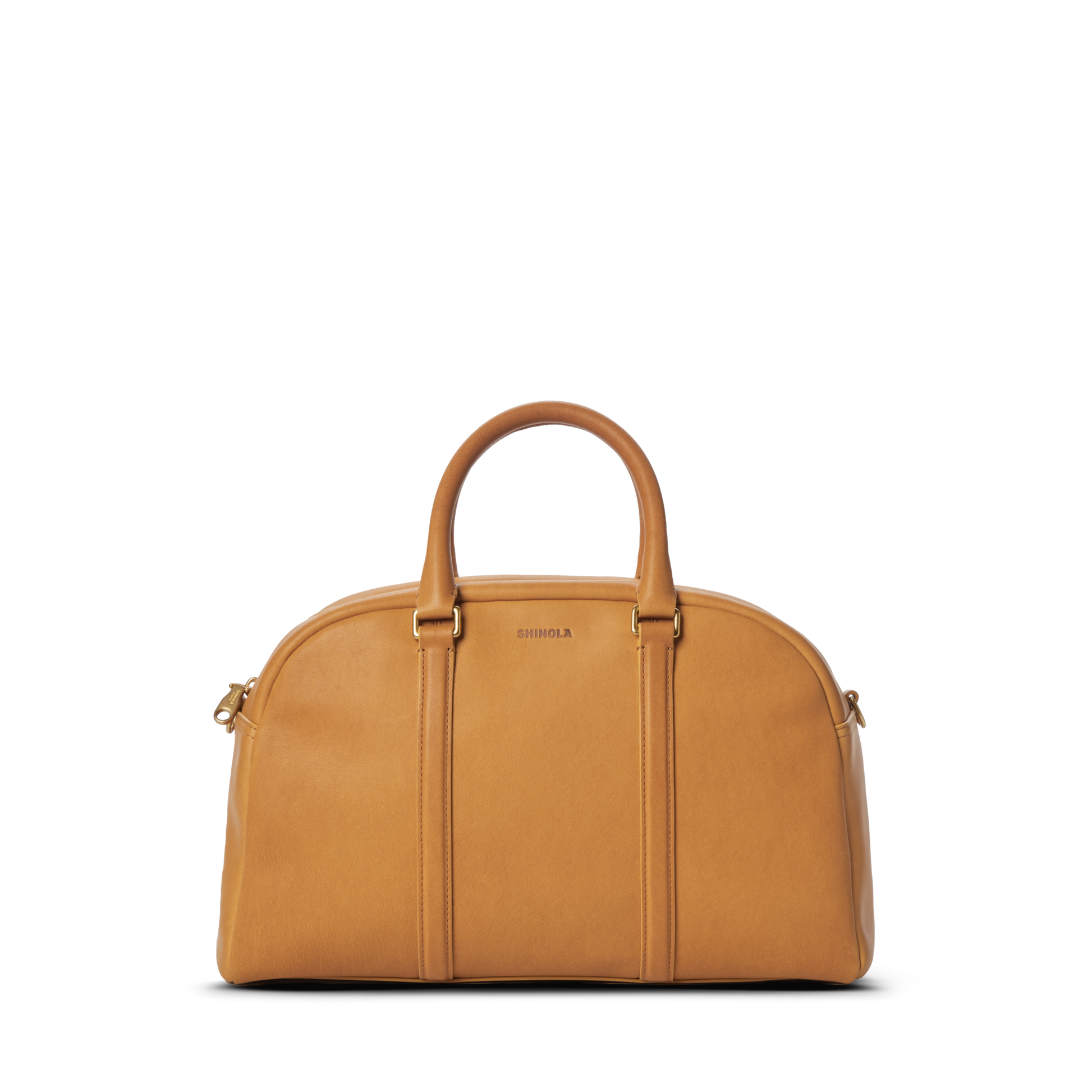 The Shinola Runwell Satchel - Honey is a tan premium natural leather duffel bag with two rounded handles, gold hardware, and a zipper closure. The front features the embossed brand name, photographed on a plain white background.