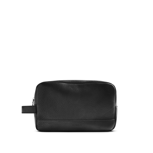 The Shinola Zip Travel Kit - Black is made from natural grain leather with a pebbled texture, featuring a zipper closure and side handle, shown on a plain white background.