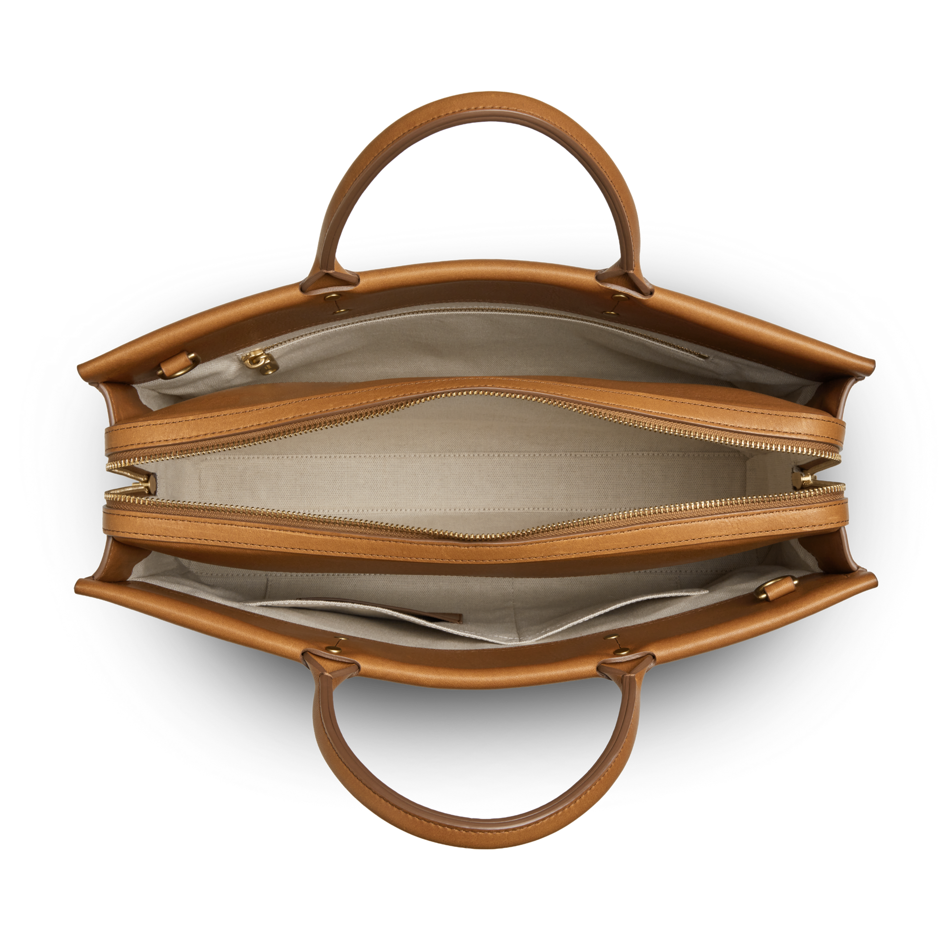 Top view of the Shinola Day Satchel - Tan: a versatile leather bag with two handles, spacious beige fabric interior, dual main compartments (one for a laptop) separated by a zip pocket, and extra small inner pockets.