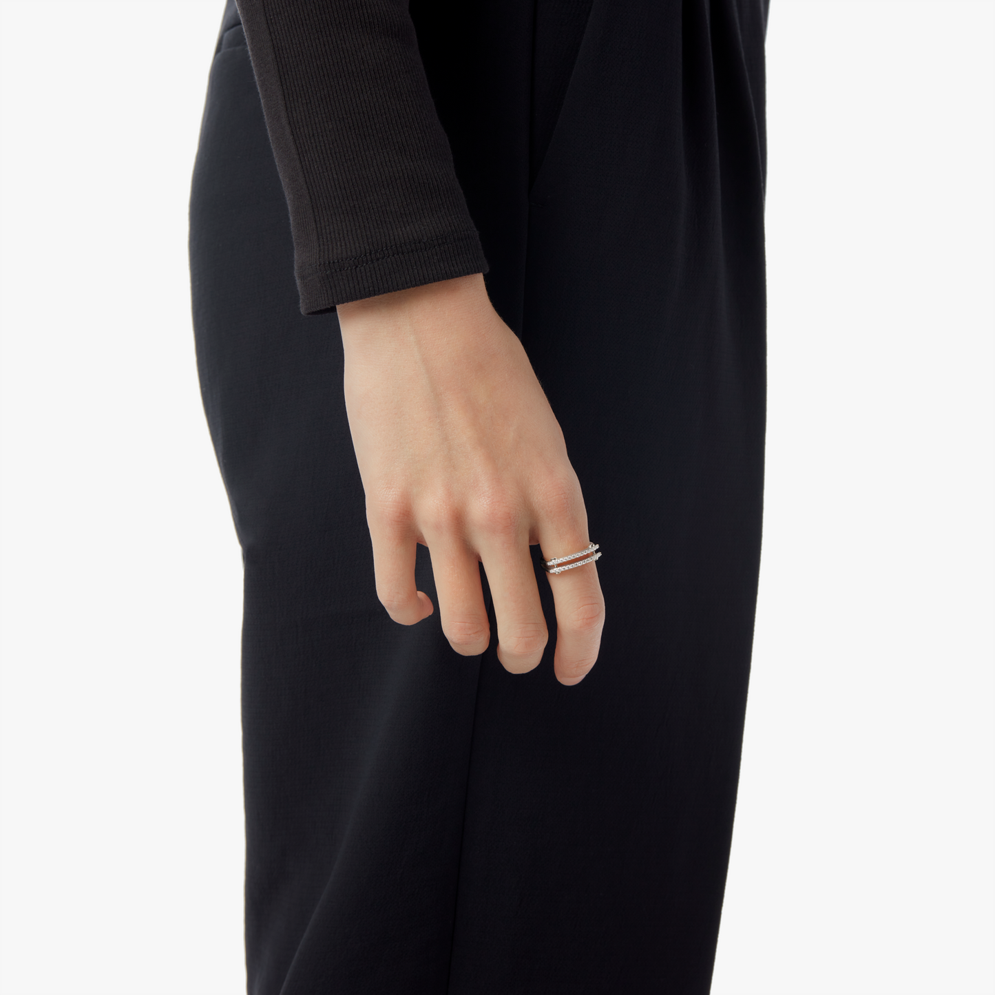 A person in a black long-sleeved outfit is shown from the waist down, hand at their side, showcasing the Shinola Diamond Pave Rivet Double Row Ring in white gold on their finger against a plain white background.