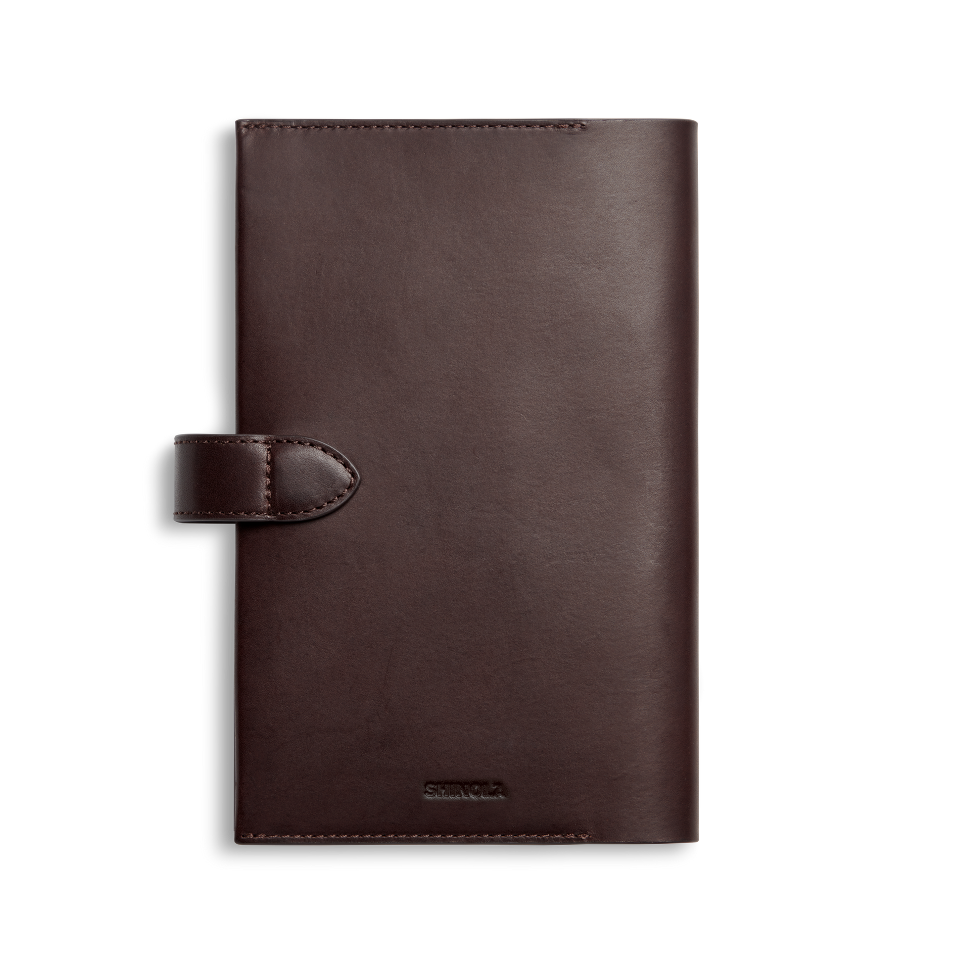 The Shinola Medium Snap Journal Cover in dark brown Vachetta leather is rectangular, featuring a buttoned strap closure, minimal stitching, and a subtle embossed logo near the bottom. Shown closed against a white background.
