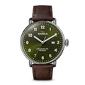The Shinola Canfield Watch - Dark Olive features a green dial with white numerals, a brown leather strap, stainless steel case, Argonite-715 movement, a date window between 3 and 4 o’clock, and “DETROIT” branding.