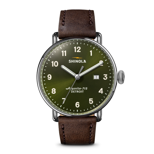 The Shinola Canfield Watch - Dark Olive features a green dial with white numerals, a brown leather strap, stainless steel case, Argonite-715 movement, a date window between 3 and 4 o’clock, and “DETROIT” branding.