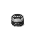A small, round tin of the Shinola Hand Poured 4oz Travel Candle - Hotel, made from coconut soy wax. The black container has white text and a silver lid, shown against a plain white background.