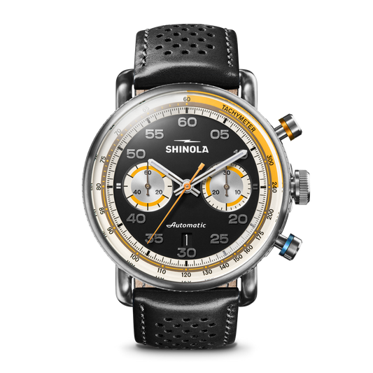 The Shinola Canfield Speedway Open Road Automatic Chronograph Watch – Black features a black leather band, black dial with yellow and silver accents, white numerals, two subdials, tachymeter scale, and silver push buttons for precise timekeeping.