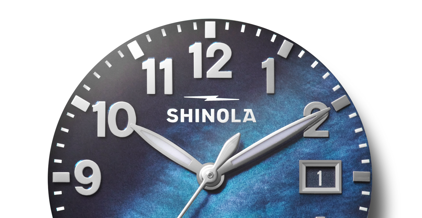 Close-up of the Shinola Runwell Watch - Cadet Blue, featuring silver hands, white hour markers, a cadet blue mother of pearl dial, and a date window at the 3 o'clock position displaying the number 1.