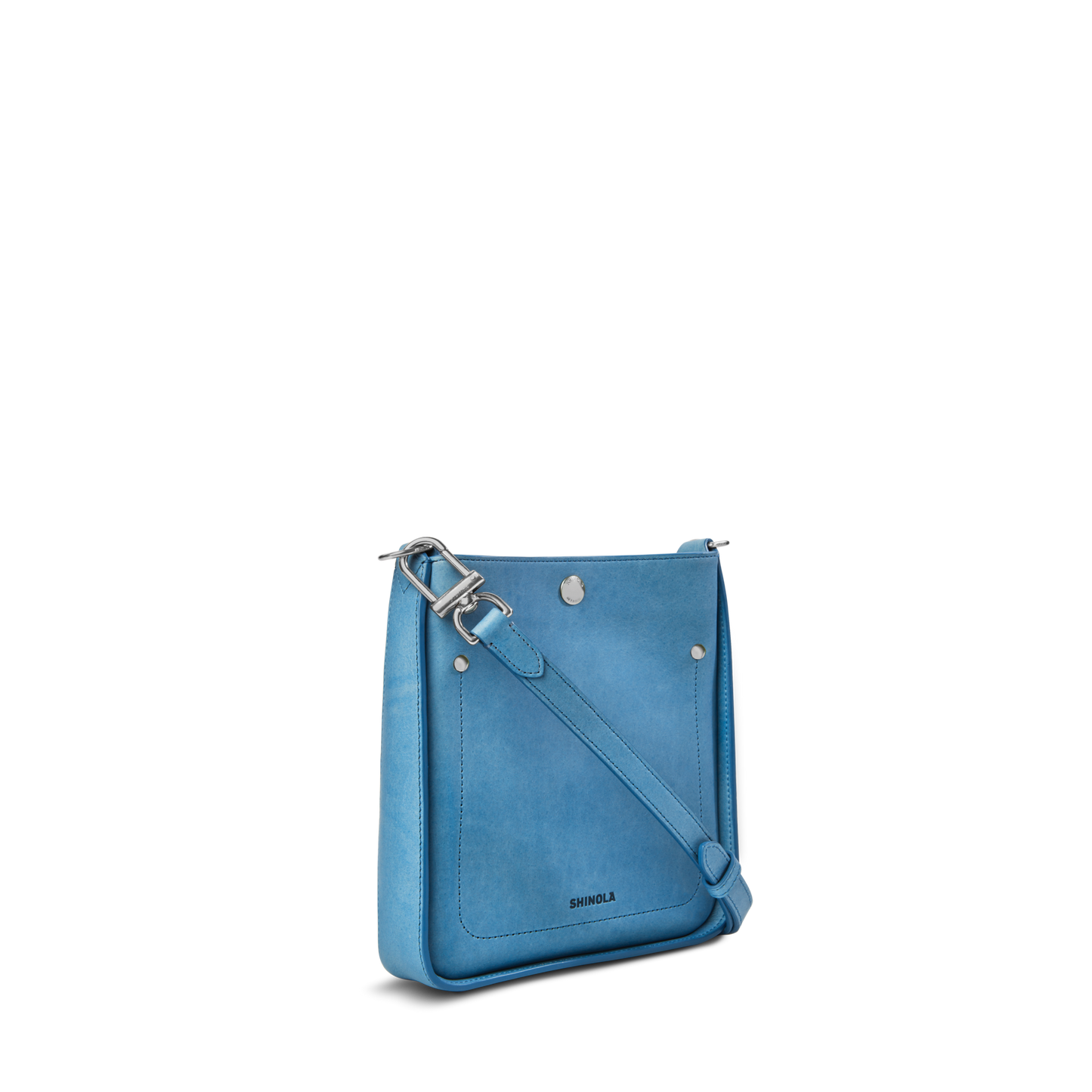 The Shinola Mini Pocket Crossbody Bag - River features light blue leather, an adjustable strap, front pocket, silver hardware, and the Shinola logo embossed on the front. Compact and stylish, it's ideal for carrying everyday essentials. Set against a white background.