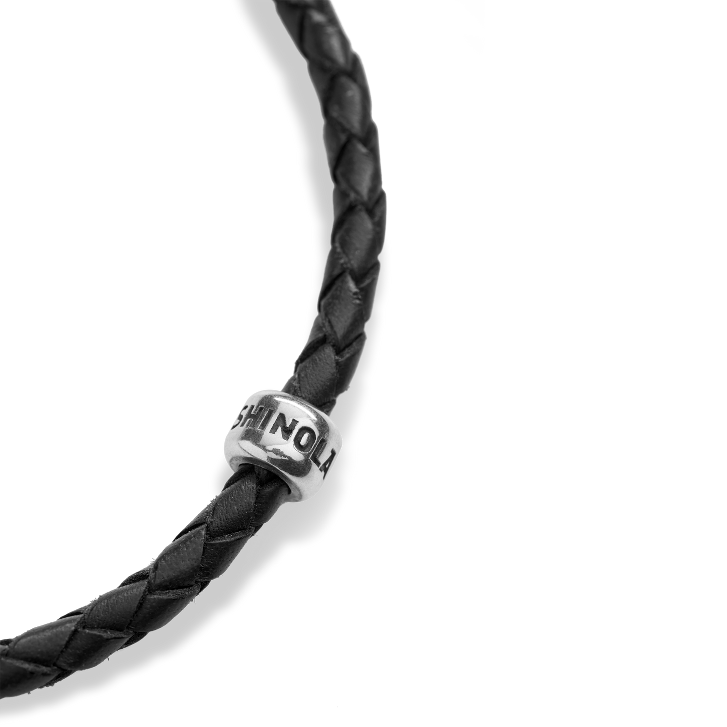 A close-up of the Shinola Single Wrap Woven Leather Bracelet in black, featuring a sterling silver clasp and a small bead engraved with "SHINOLA," set against a plain white background.