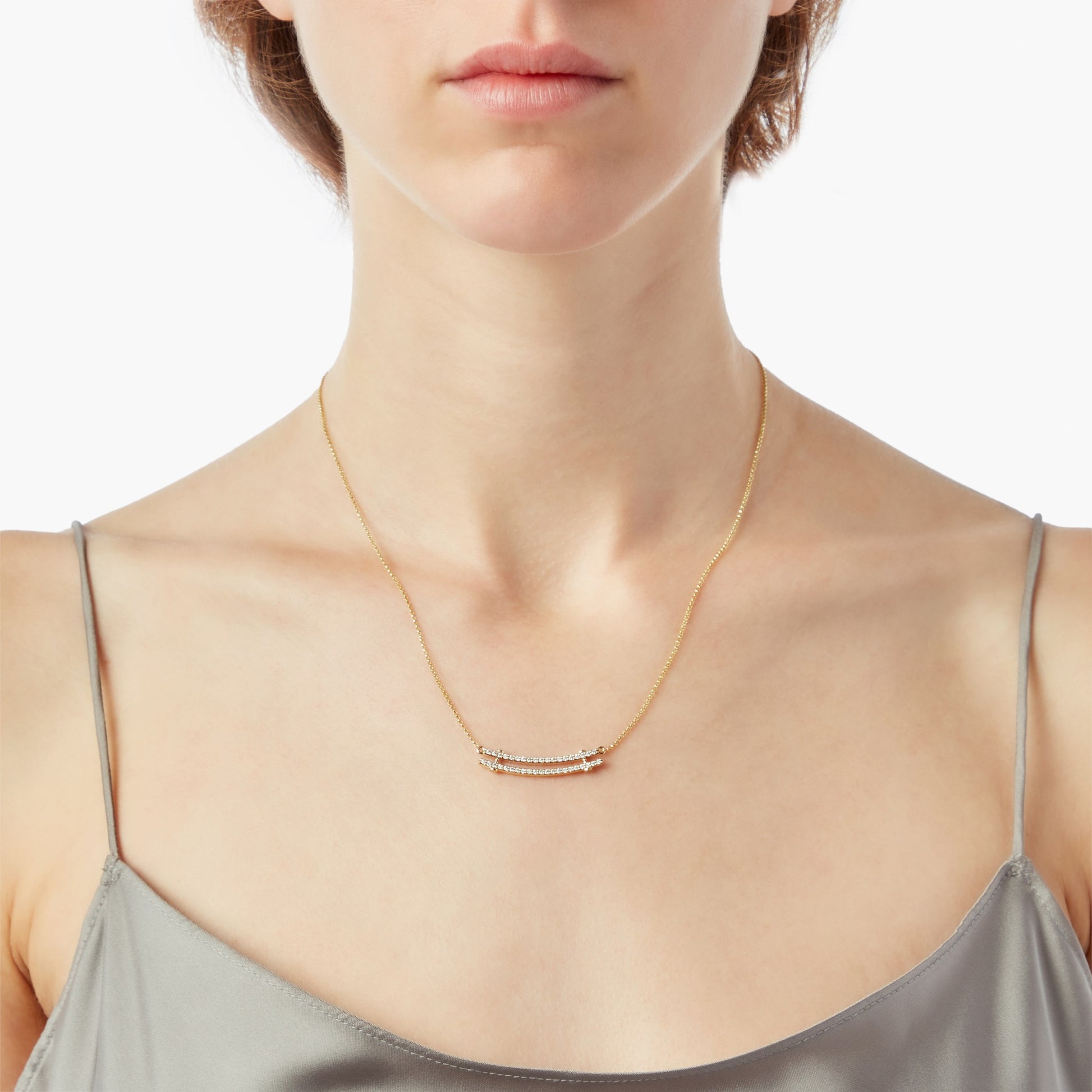 A woman wears the Shinola Diamond Pave Rivet Double Row Necklace in 14k yellow gold, styled with a silky gray spaghetti strap top against a plain white background.