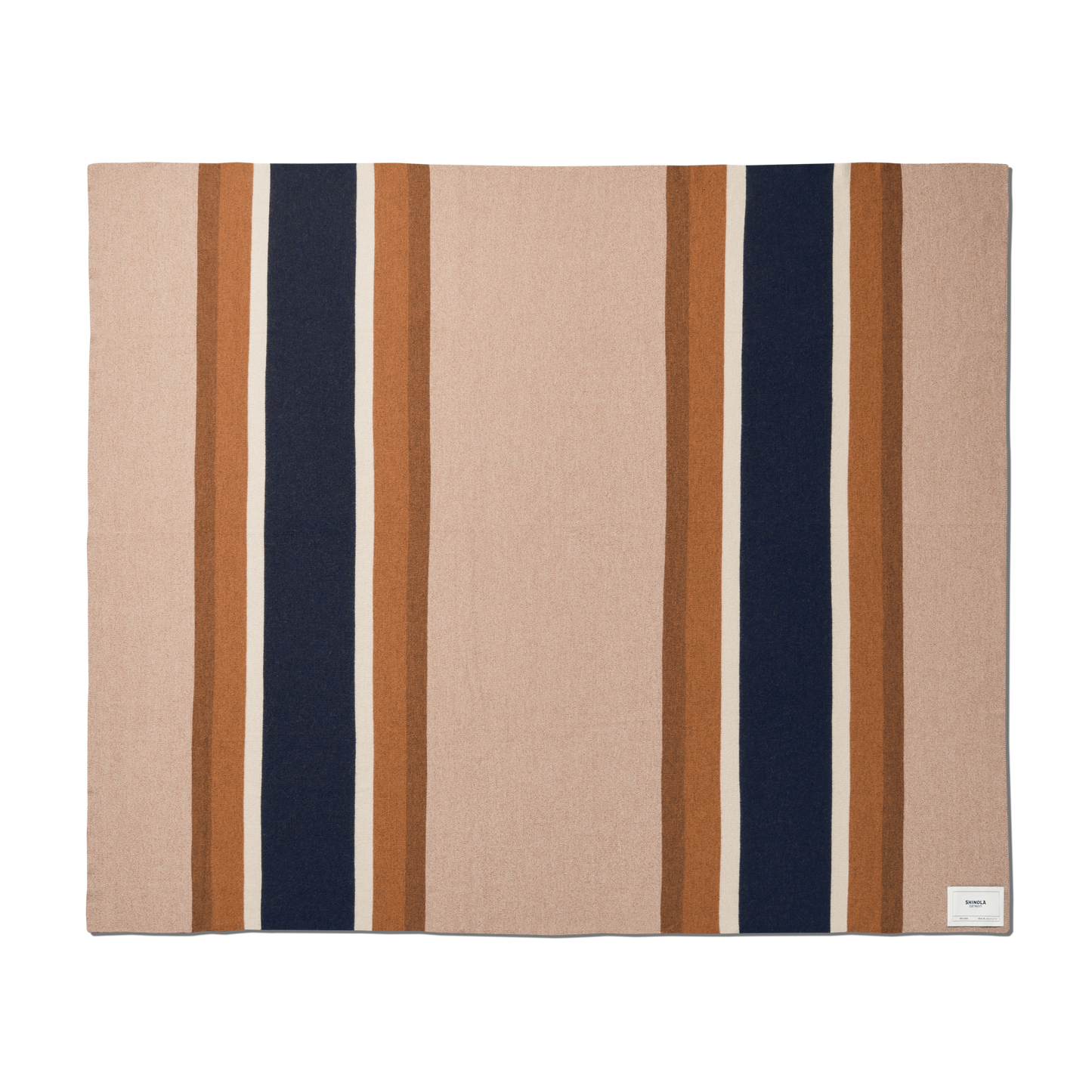 The Shinola Alpaca Throw Blanket in pink and beige is a rectangular blanket featuring wide vertical navy and brown stripes, bordered by thin light brown stripes, with a small white label sewn in one corner.