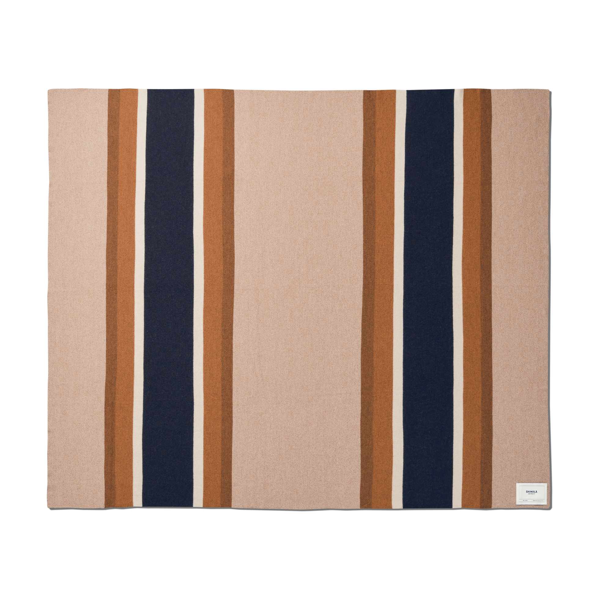 The Shinola Alpaca Throw Blanket in pink and beige is a rectangular blanket featuring wide vertical navy and brown stripes, bordered by thin light brown stripes, with a small white label sewn in one corner.