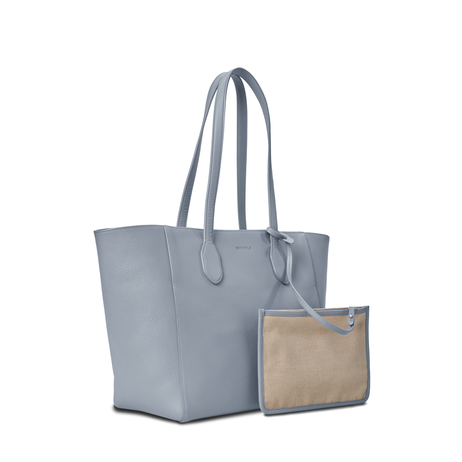 The Shinola Runabout Tote Bag - Mist features light blue pebbled leather and long handles, shown with a detachable beige and blue zip pouch in front, displayed against a plain white background.