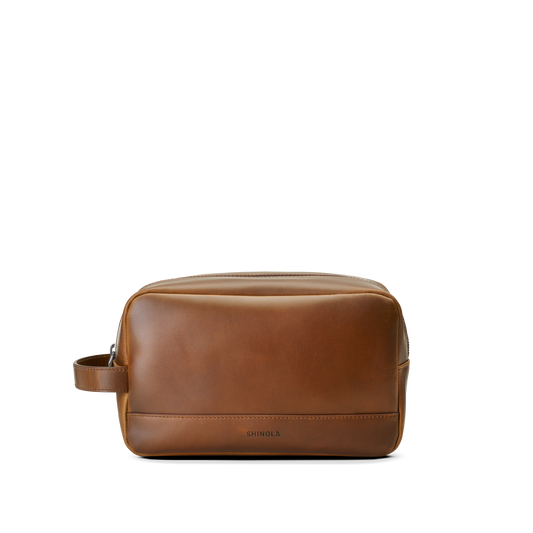 The Zip Travel Kit - Medium Brown by Shinola features navigator leather and a side handle, shown on a plain white background. Shinola’s brand name is subtly embossed near the lower front.