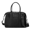 The Shinola Runabout Holdall Canvas Bag in black features cotton canvas, two short handles, a detachable crossbody strap, a zippered top, a subtle front logo patch, and silver hardware accents.