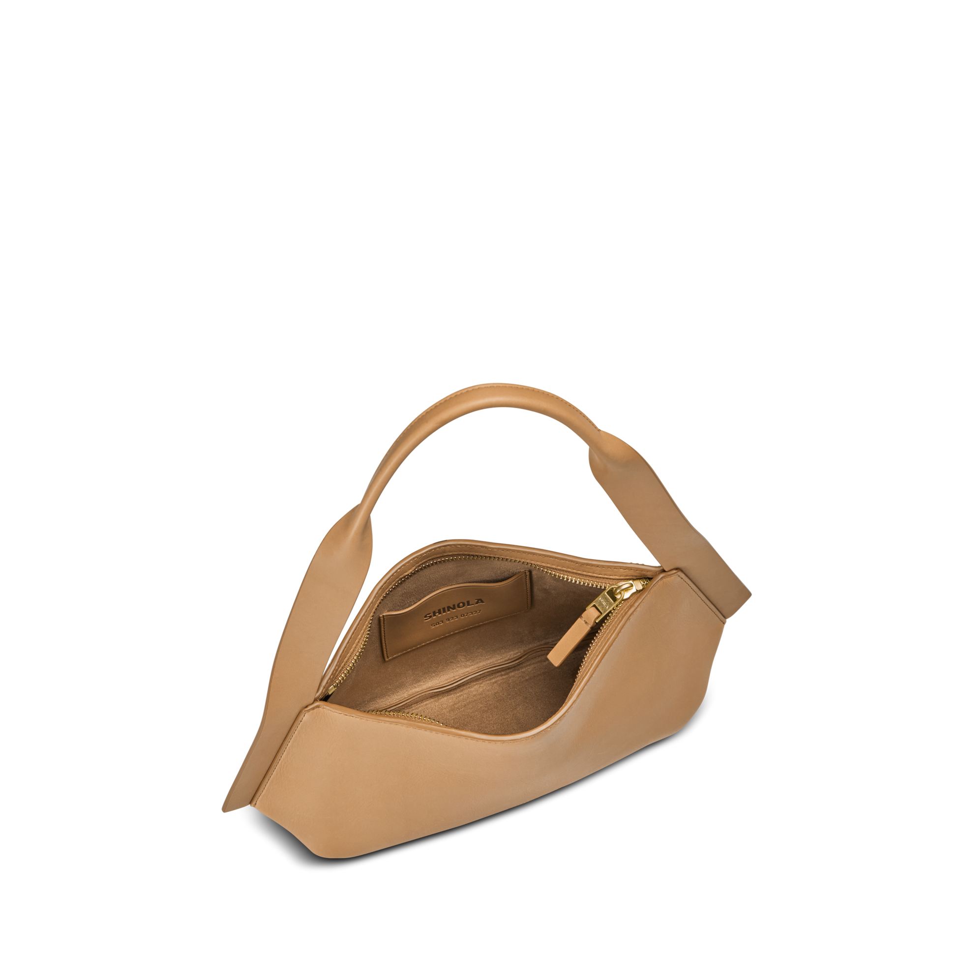 The Small Derby Shoulder Bag - Honey by Shinola features sculptural, asymmetrical tan leather, a beige interior with internal pocket and brand label, and is shown partially unzipped against a plain white background.