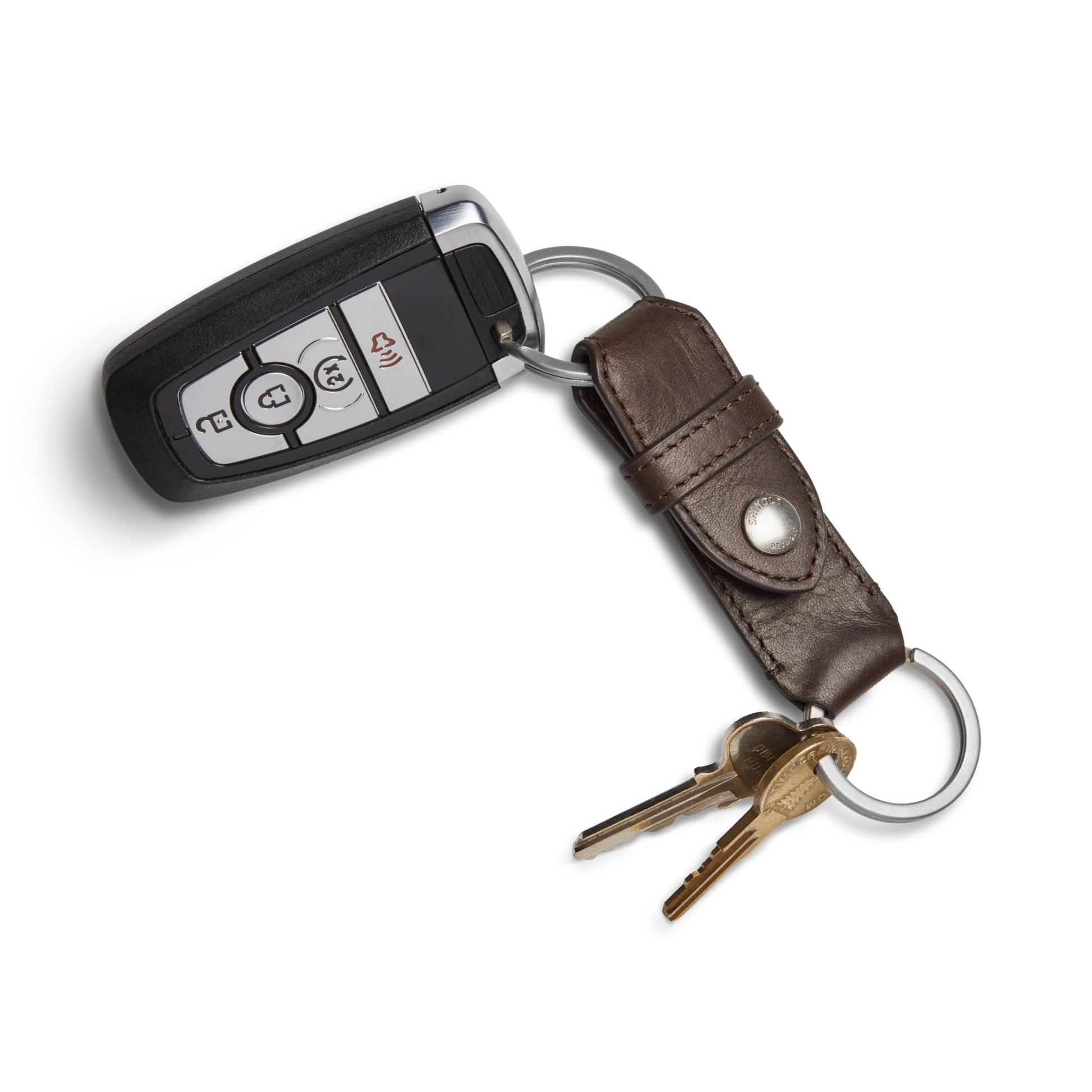 The Shinola Leather Valet Key Fob in Dark Brown holds a car key fob with multiple buttons and two brass house keys on a silver ring, displayed against a white background.