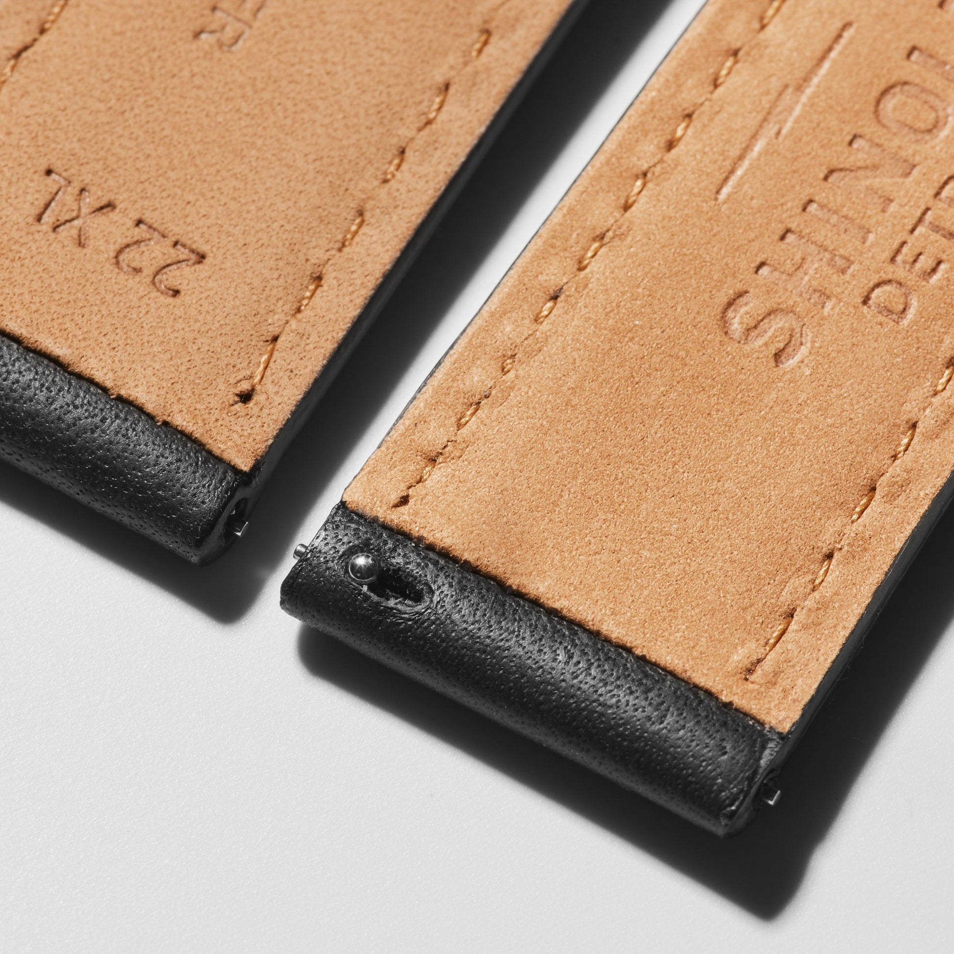Close-up of two Shinola QR Strap: 22/20 XL Aniline, RR Classic, PoSS - Black leather watch bands with black edges and detailed stitching. Embossed text and size markings highlight the craftsmanship in bright lighting.