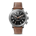 The Shinola Runwell Chronograph Watch - Black features a black dial with white numerals, three subdials, a date window, and a brown leather strap. Its stainless steel silver case is complemented by three side buttons.
