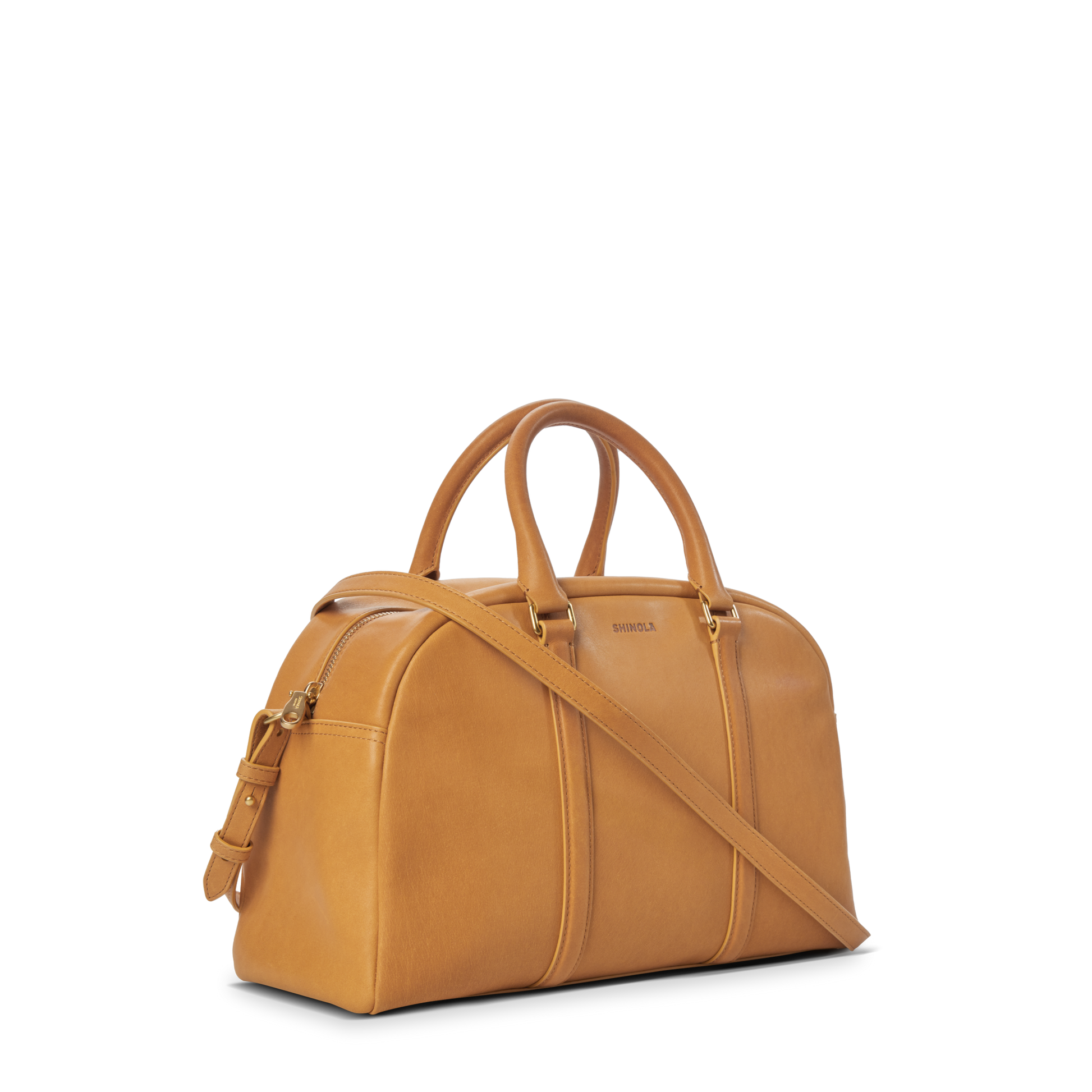 The Shinola Runwell Satchel - Honey is crafted from premium natural leather with two short handles, a long adjustable strap, and a structured, rounded silhouette. Its minimalistic design is highlighted against a plain white background.