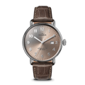 The Shinola Canfield Watch features a 38mm round silver case, tan dial with silver markers, numerals, hands, and date window at 3 o’clock. It comes with a gray-brown American alligator leather strap and runs on the Argonite 705 movement.