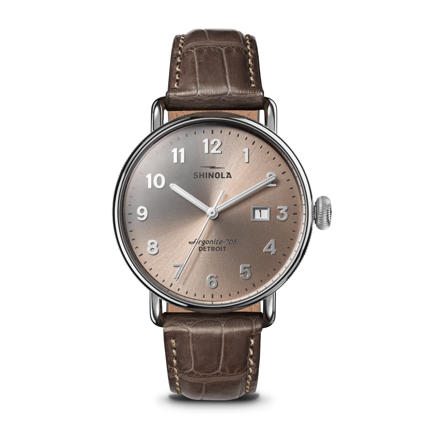 The Shinola Canfield Watch features a 38mm round silver case, tan dial with silver markers, numerals, hands, and date window at 3 o’clock. It comes with a gray-brown American alligator leather strap and runs on the Argonite 705 movement.