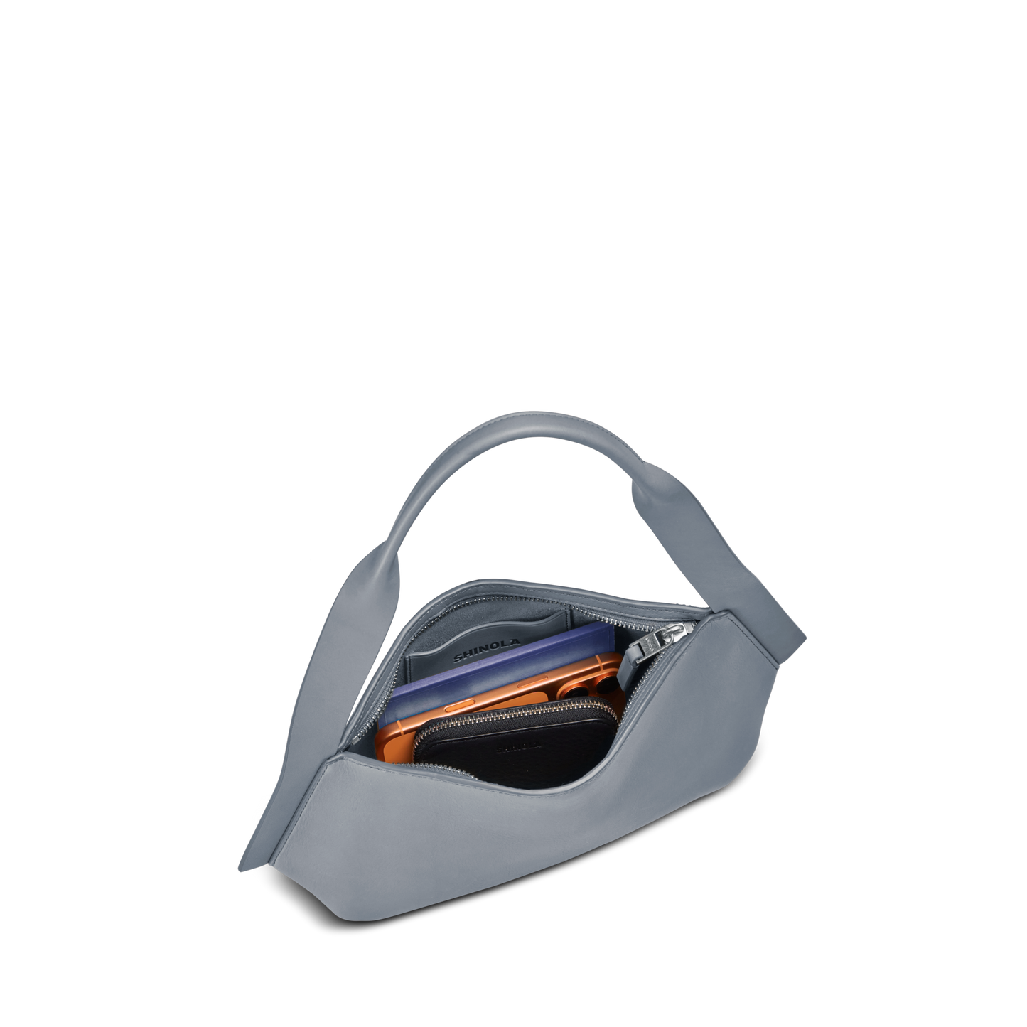 The Small Derby Shoulder Bag - Mist by Shinola is a light gray, naturally crafted leather bag with a curved handle, open to show a wallet, smartphone, and zipped pouch inside against a white background.