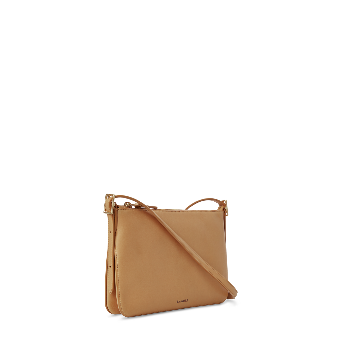 The Shinola Small Bixby Crossbody - Honey is a slim tan leather bag with an adjustable strap and gold hardware, designed as an ideal everyday accessory and shown against a clean white background.