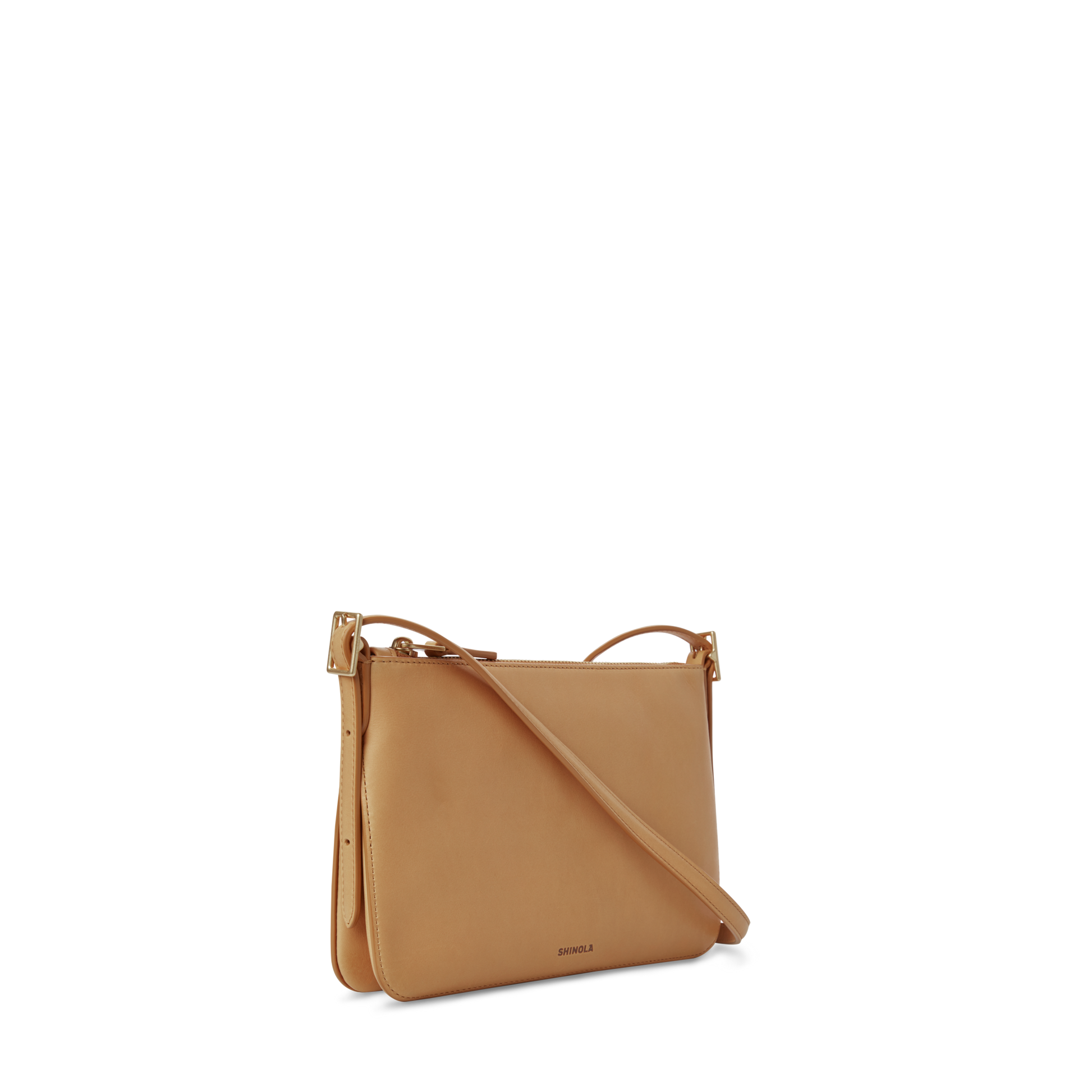 The Shinola Small Bixby Crossbody - Honey is a slim tan leather bag with an adjustable strap and gold hardware, designed as an ideal everyday accessory and shown against a clean white background.