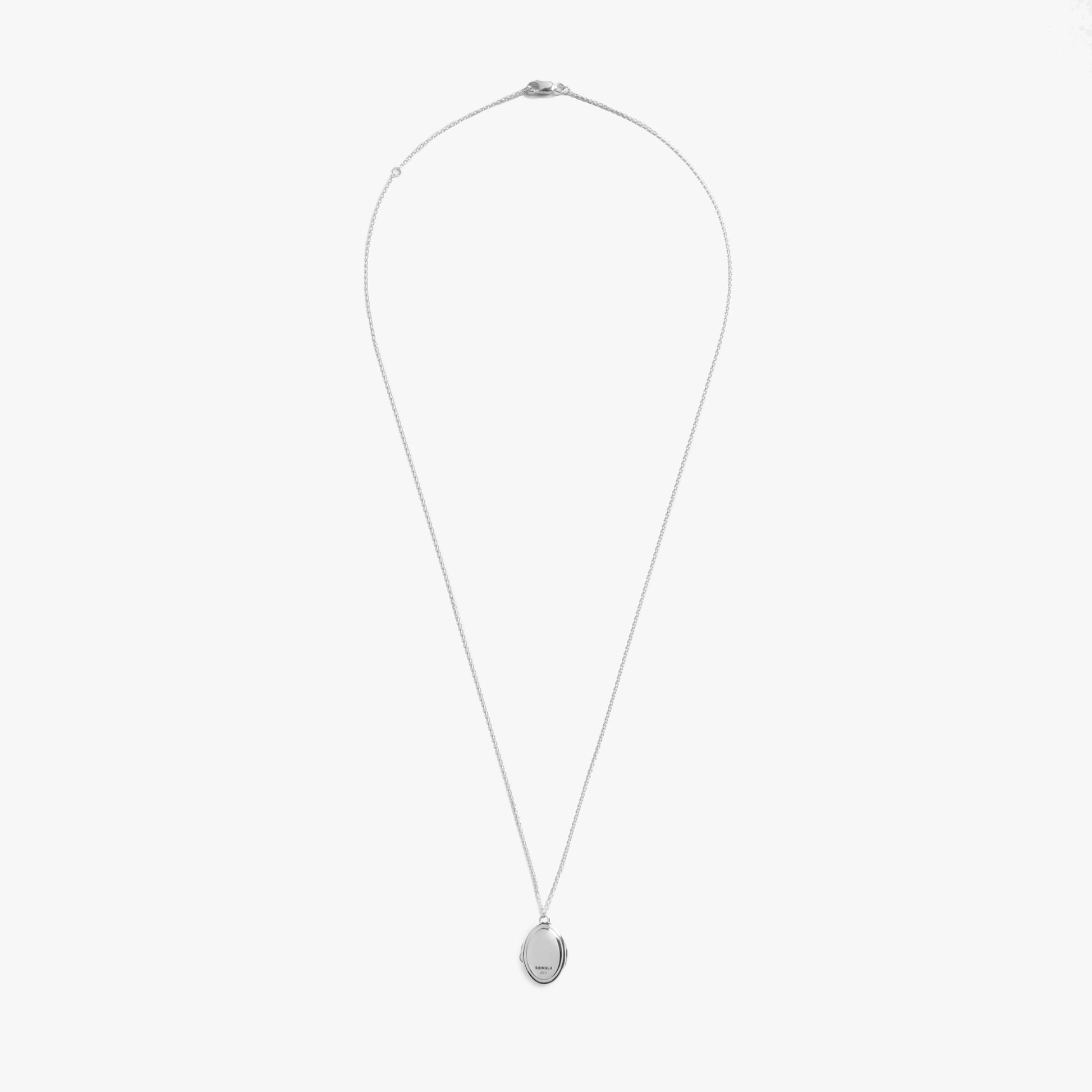 The Shinola Heirloom Petite Locket Necklace in sterling silver features a fine chain and an engravable oval pendant, shown against a plain white background.