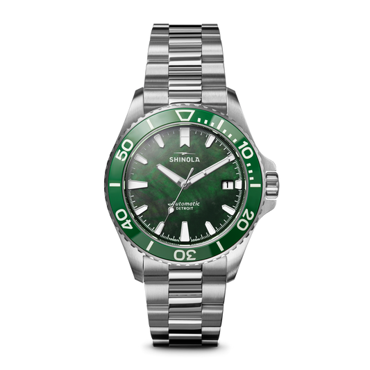 The Shinola Lake Ontario Monster Automatic Dive Watch features a stainless steel case, green bezel and dial, silver markers and hands, and a silver metal link bracelet with an automatic movement indicator on the watch face.