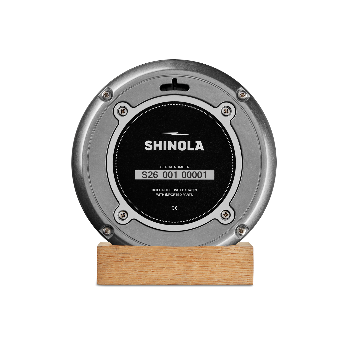 The 6" Runwell Clock by Shinola features a round, tumbled zinc case and black center, set on a light wooden base and displayed against a plain white background.