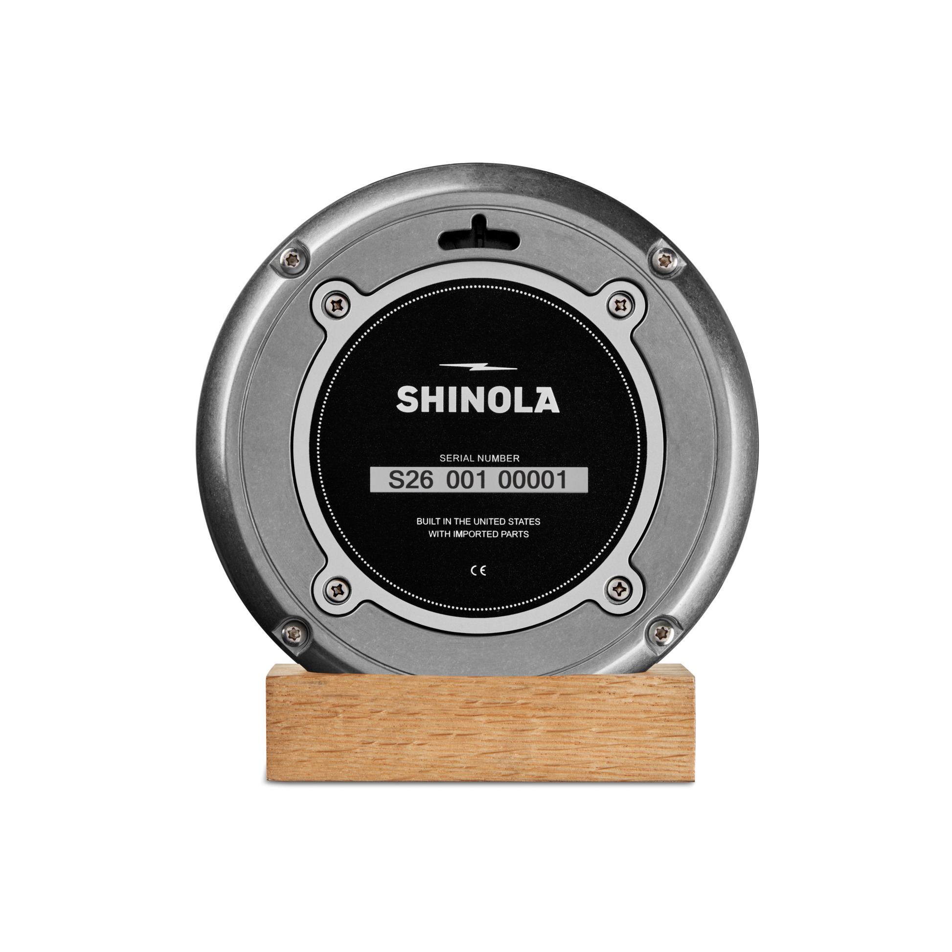The 6" Runwell Clock by Shinola features a round, tumbled zinc case and black center, set on a light wooden base and displayed against a plain white background.