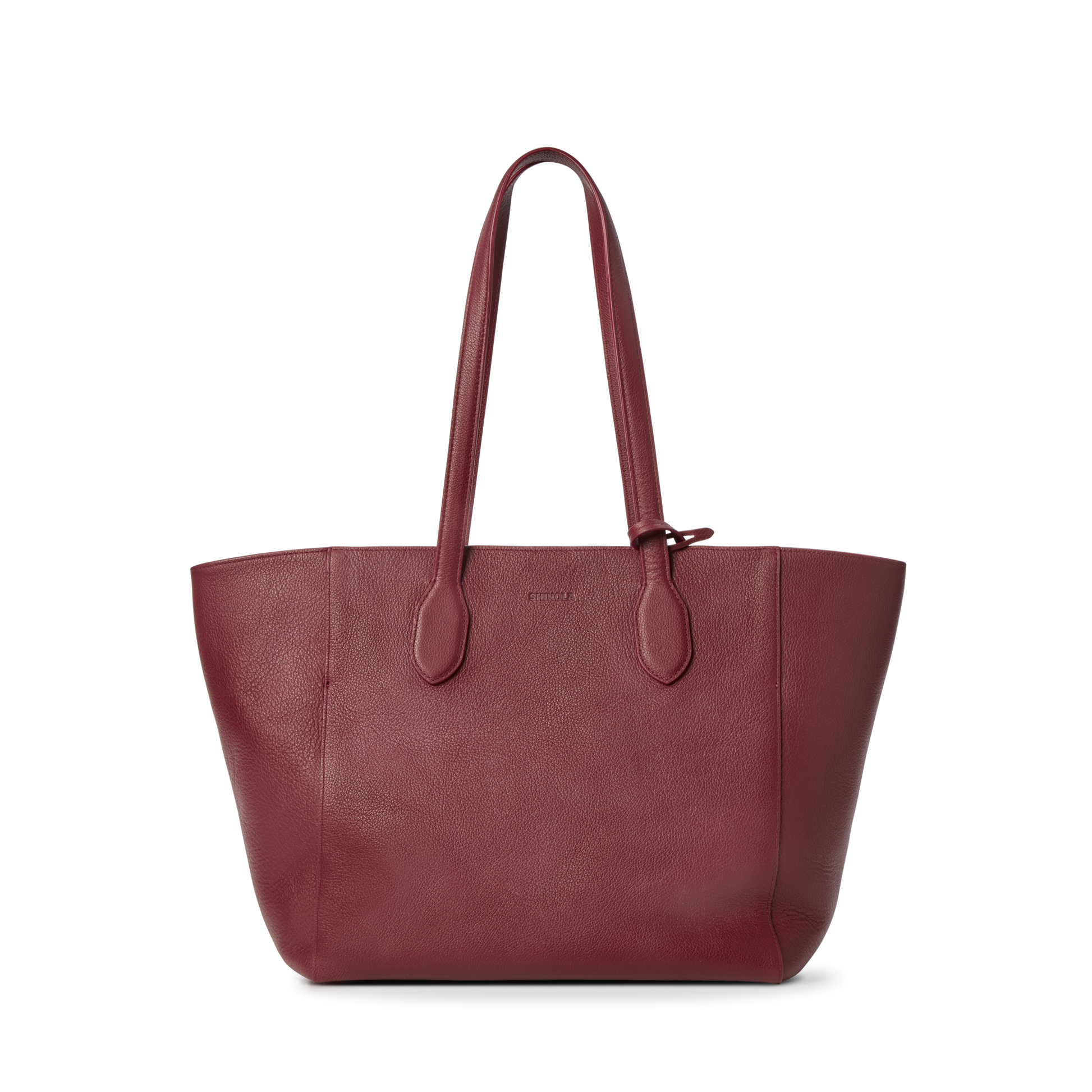 The Shinola Runabout Tote Bag - Ruby is a large, deep red pebbled leather tote with two long handles, a textured surface, and minimalistic design. Lightweight and practical, it includes an interior zipper pouch. Shown on a plain white background.