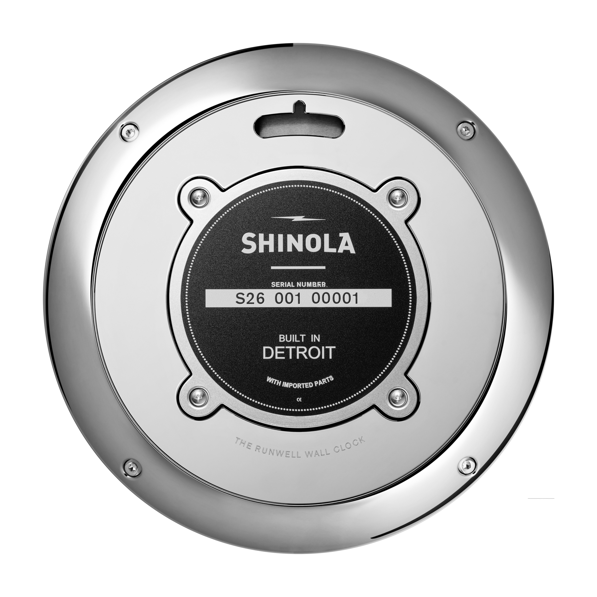 A close-up of the back of a Shinola 14" Runwell Clock - Black shows its round chrome casing and a black label displaying the serial number and stating "Built in Detroit with imported parts.