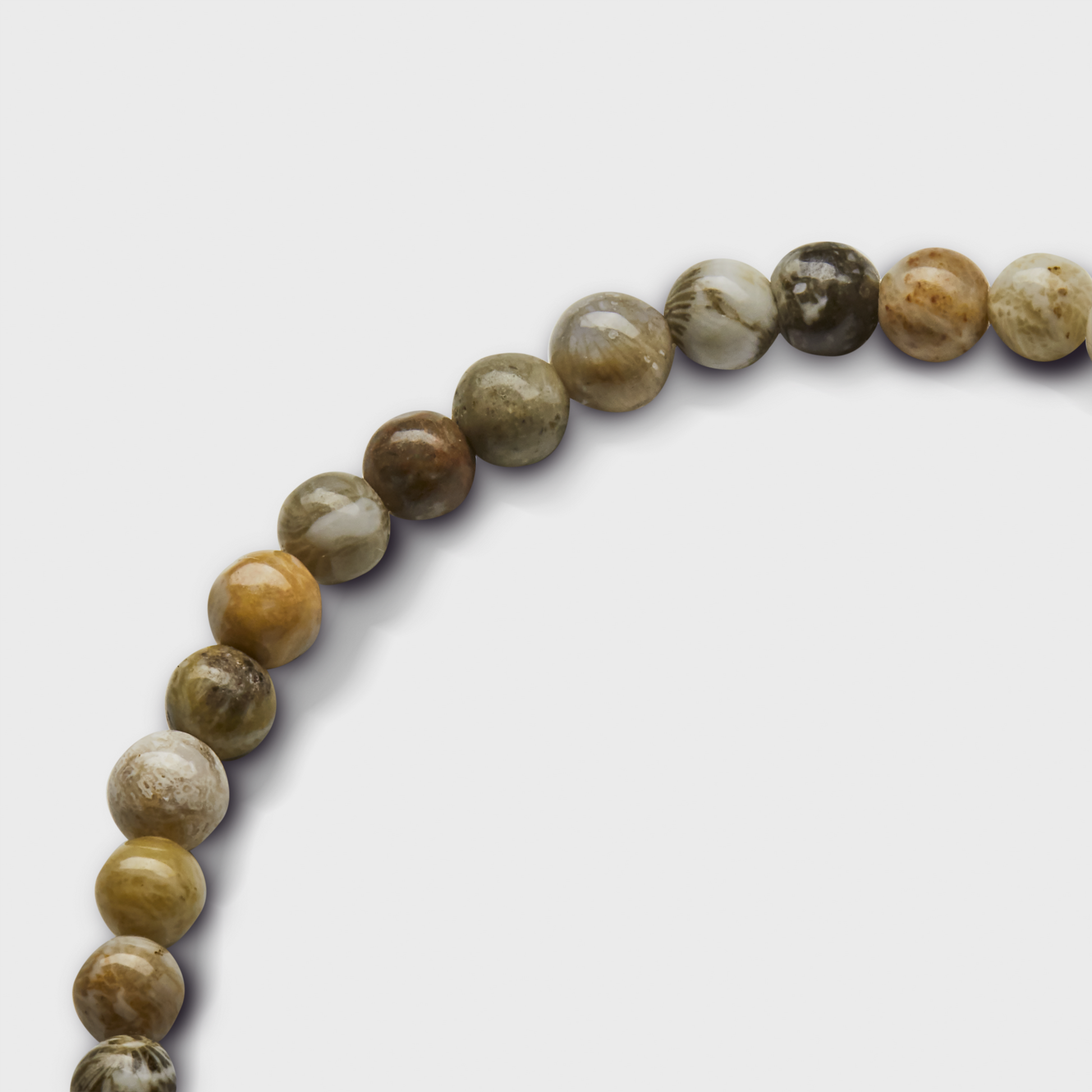 The Shinola 4mm Beaded Petoskey Bracelet features polished round Petoskey stone beads in brown, tan, and gray with a sterling silver accent, shown on a white background.