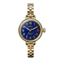 The Shinola Birdy Watch - Lapis features a gold-tone case, blue lapis-inspired textured dial with gold hour markers, and a matching gold metal link band, shown on a plain white background.