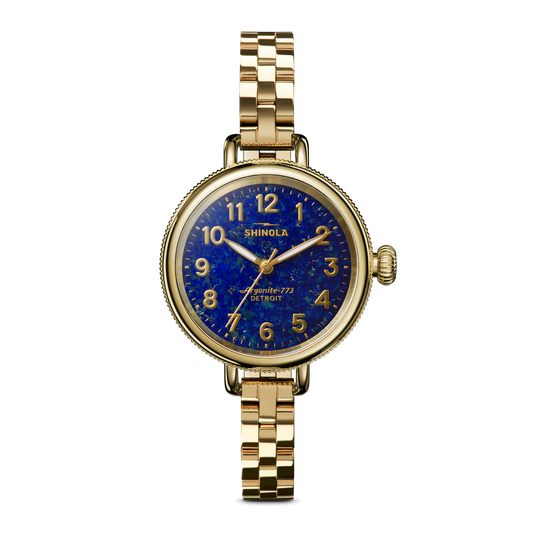 The Shinola Birdy Watch - Lapis features a gold-tone case, blue lapis-inspired textured dial with gold hour markers, and a matching gold metal link band, shown on a plain white background.
