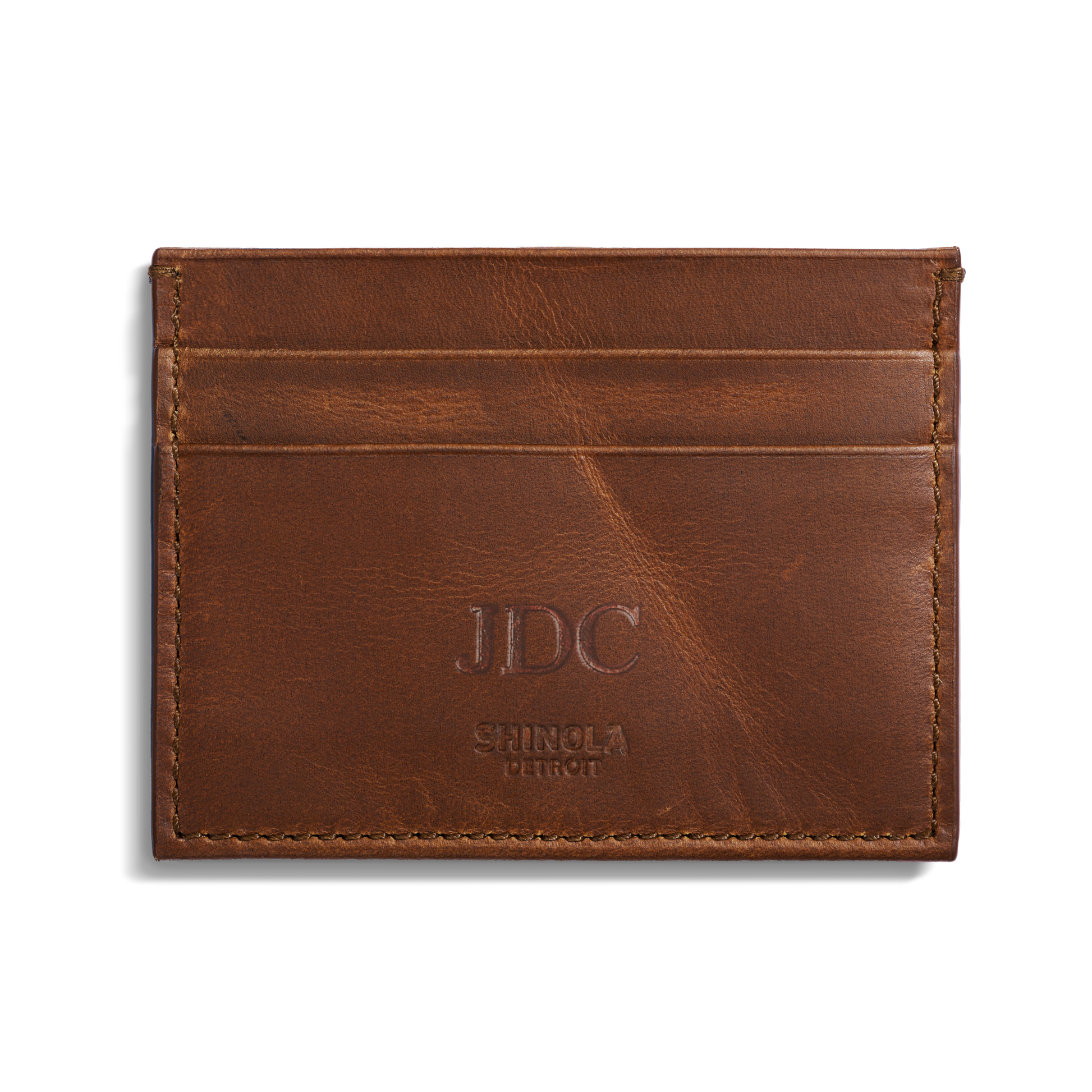 The Shinola 5 Pocket Card Holder in medium brown leather, embossed with JDC initials and "Shinola Detroit" on the front, features two slots and offers a stylish way to carry your credit cards.