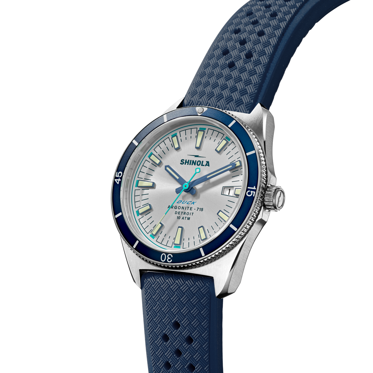The Shinola Duck Watch - Midnight Blue features a stainless-steel case, blue bezel, white dial, turquoise hands, and a textured blue rubber strap, displayed at an angle on a plain white background.
