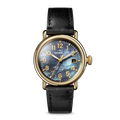 The Shinola Runwell Watch features a MOP black leather strap, dark iridescent face, gold numerals and hands, and a gold-tone stainless steel case, shown against a plain light background.