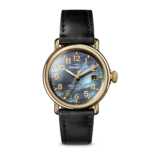 The Shinola Runwell Watch features a MOP black leather strap, dark iridescent face, gold numerals and hands, and a gold-tone stainless steel case, shown against a plain light background.