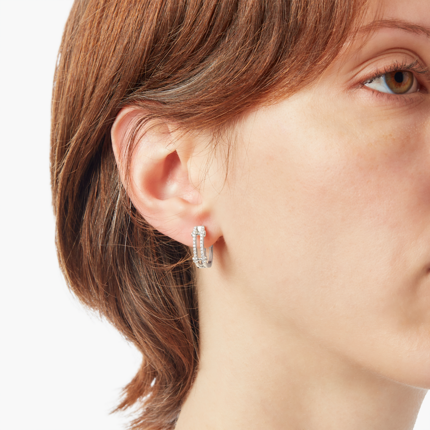 Close-up of a person with short brown hair wearing Shinola Diamond Pave Rivet Double Row Hoop Earrings in 14k White Gold in their left ear, shown against a white background.