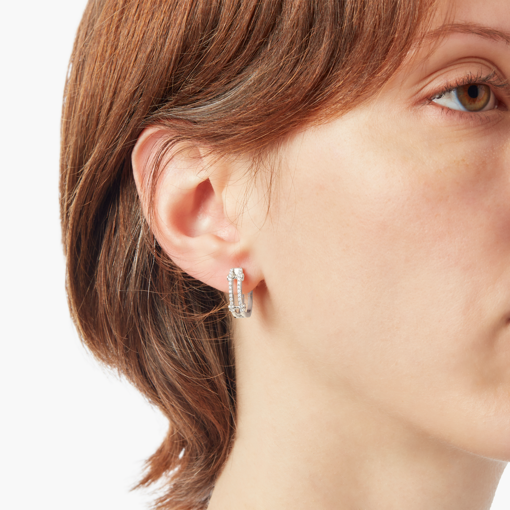 Close-up of a person with short brown hair wearing Shinola Diamond Pave Rivet Double Row Hoop Earrings in 14k White Gold in their left ear, shown against a white background.