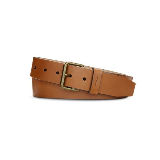 The Shinola 1 1/2" Rambler Belt in tan bridle leather features a brass buckle and is shown coiled on a plain white background.