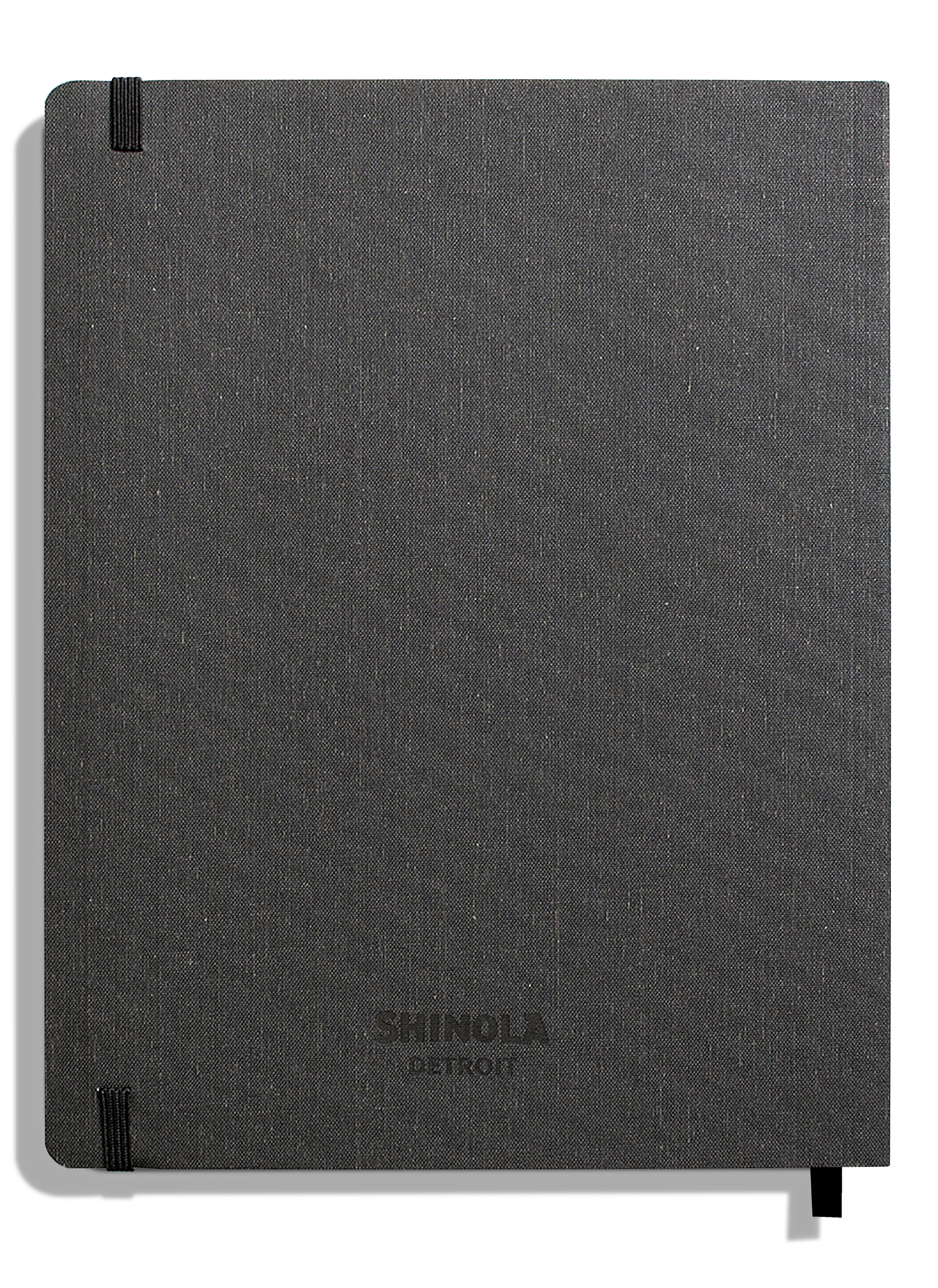 A closed, charcoal linen-bound Large Soft Ruled Journal by Shinola, with smyth-sewn binding and black elastic closures on the top left and bottom right corners.